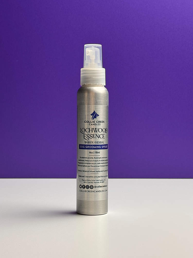 Silver aluminum misting spray bottle with clear cap on a white table with a purple background.