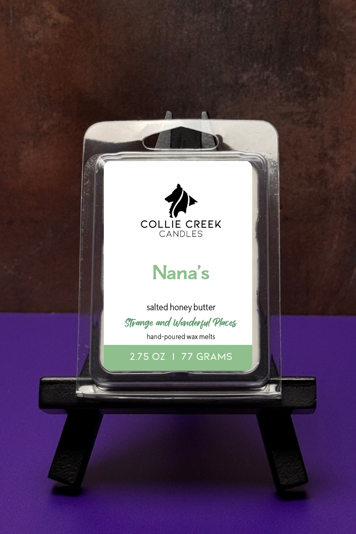 Collie Creek Candles Nana's wax melt packaging on a stand with a worn bronze and purple background
