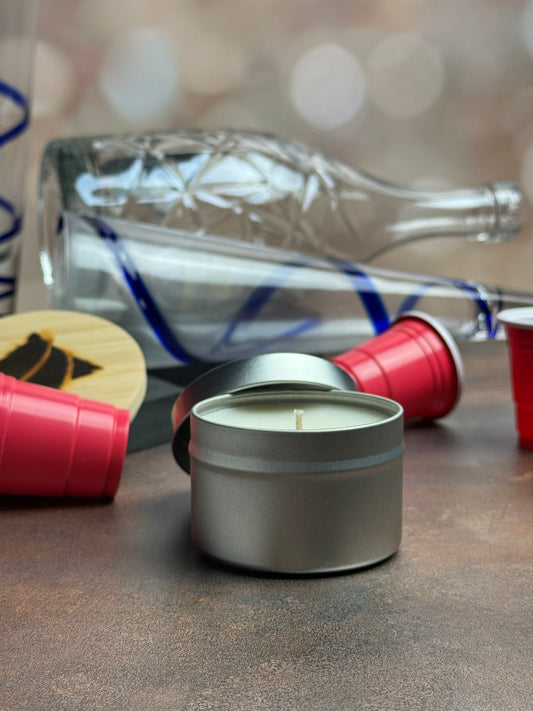 New Year Pawty tin candle with remnants of a party in the background - red cups, empty champagne bottle and glasses.