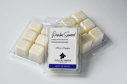 Grouping of three wax melt clamshells. All wax in natural coloring. Two clam shells are label down showing 6 1 inch cubes.Center clamshell is labeled Psychic Squirrel, a creamy, white birch tree fragranced hand poured wax melt.