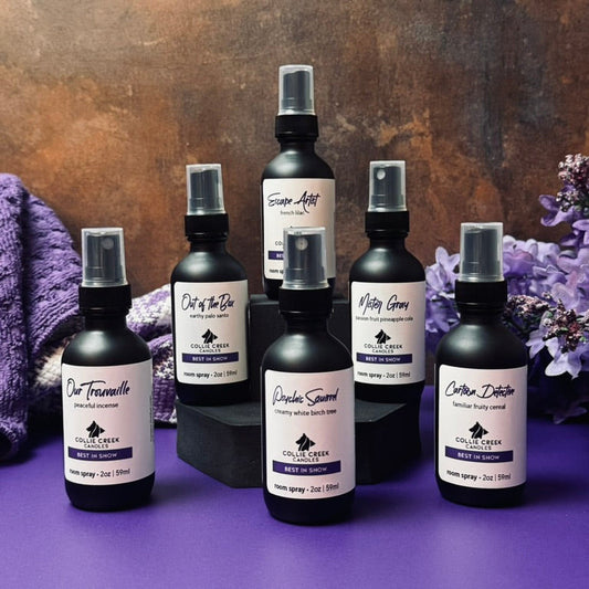 Collection of black spray bottles with labels on a purple surface and bronze background
