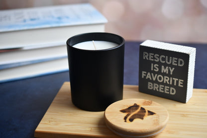 8 ounce candle in matte black vessel on a wooden cutting board. A wood burned logo candle lid in foreground.