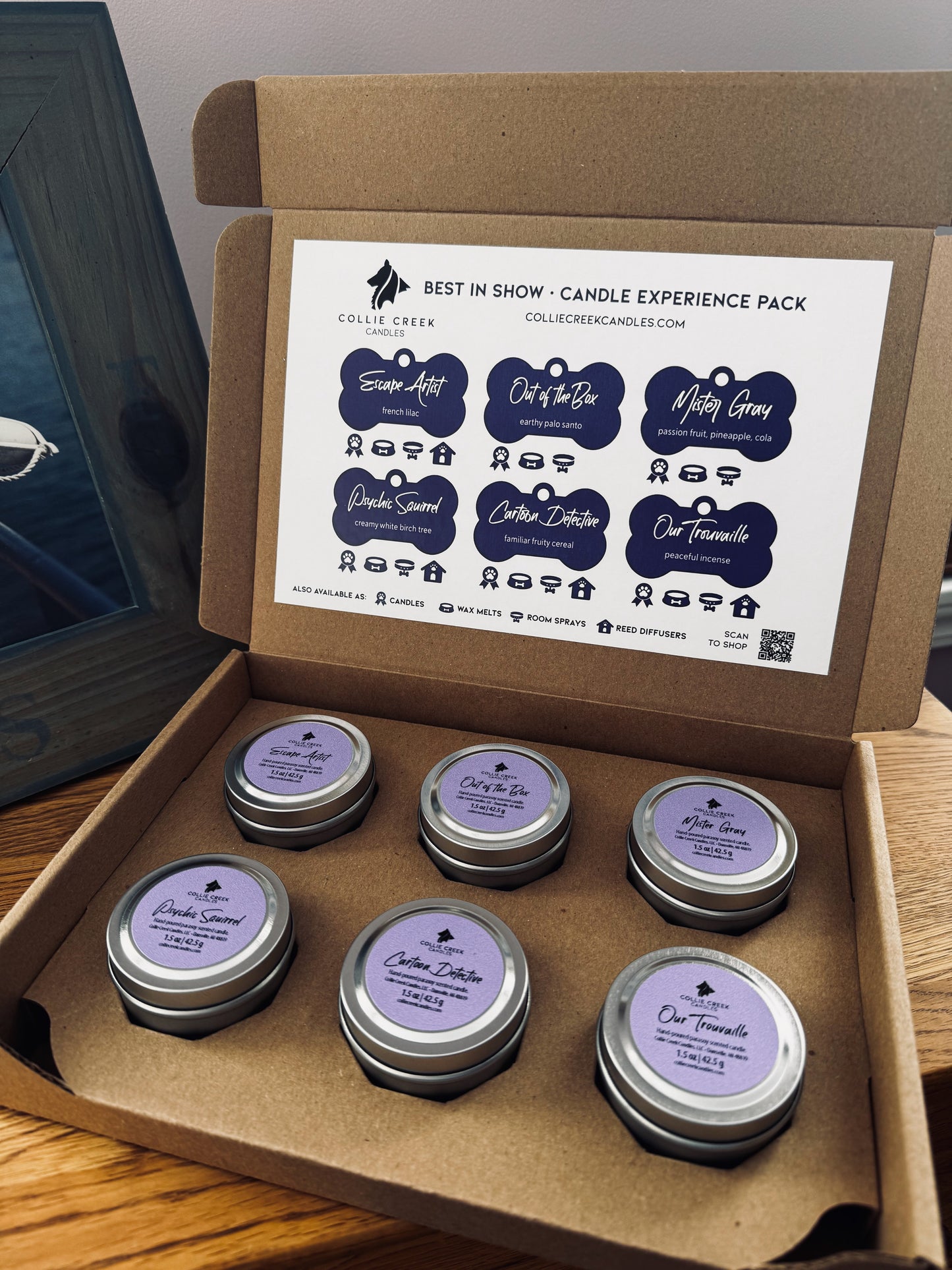 Box of candle samples with purple labels on a wooden surface