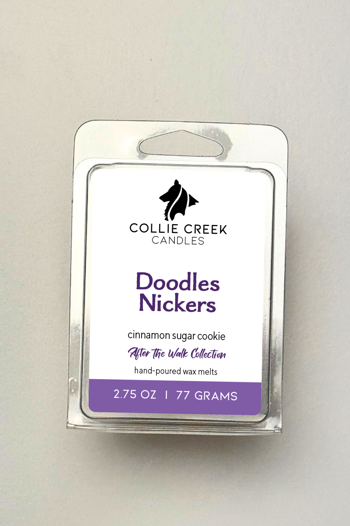 Single wax melt in a clear clam shell on a white background, Doodles Nickers in purple on the label
