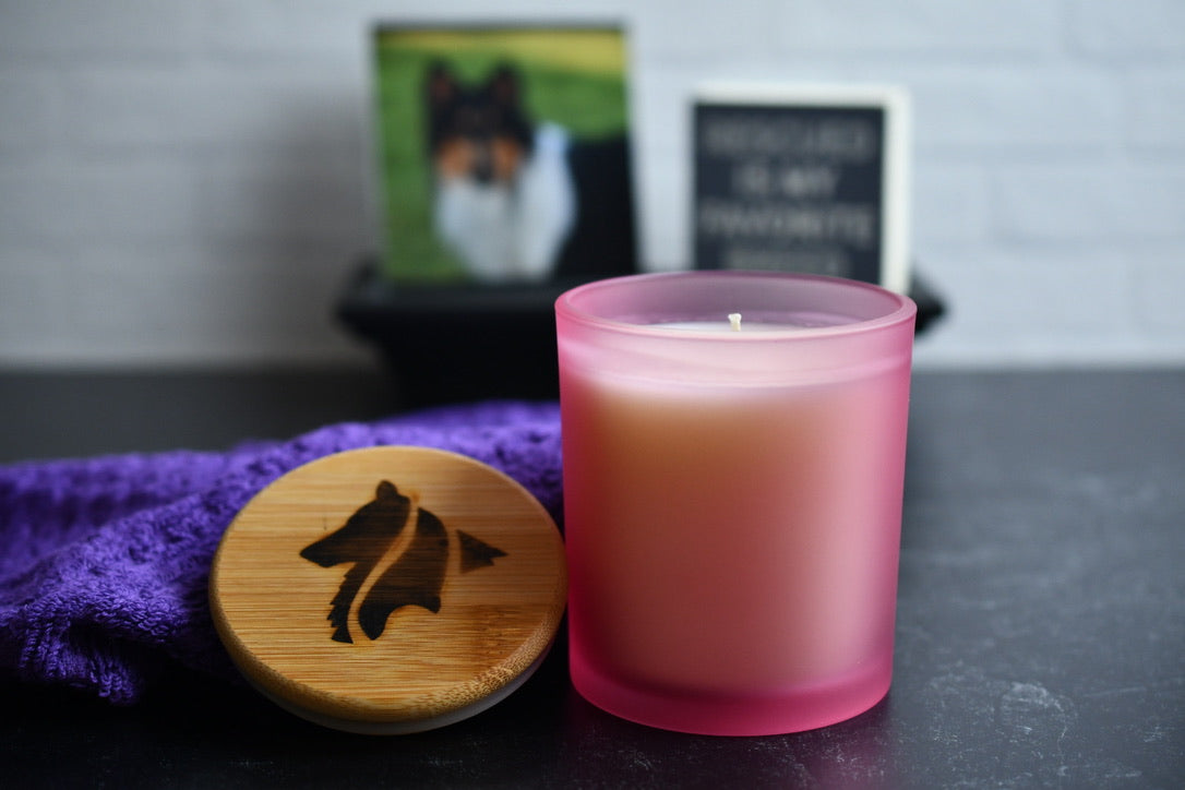 Pink candle with wooden lid on a dark surface, with blurred background