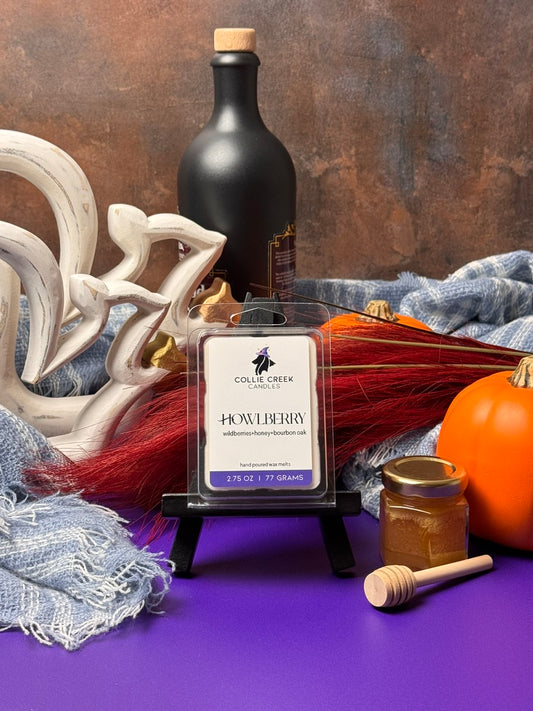 Collie Creek Howlberry wax melts product with decorative jar of honey and wooden dipper, and various fall elements on a purple surface