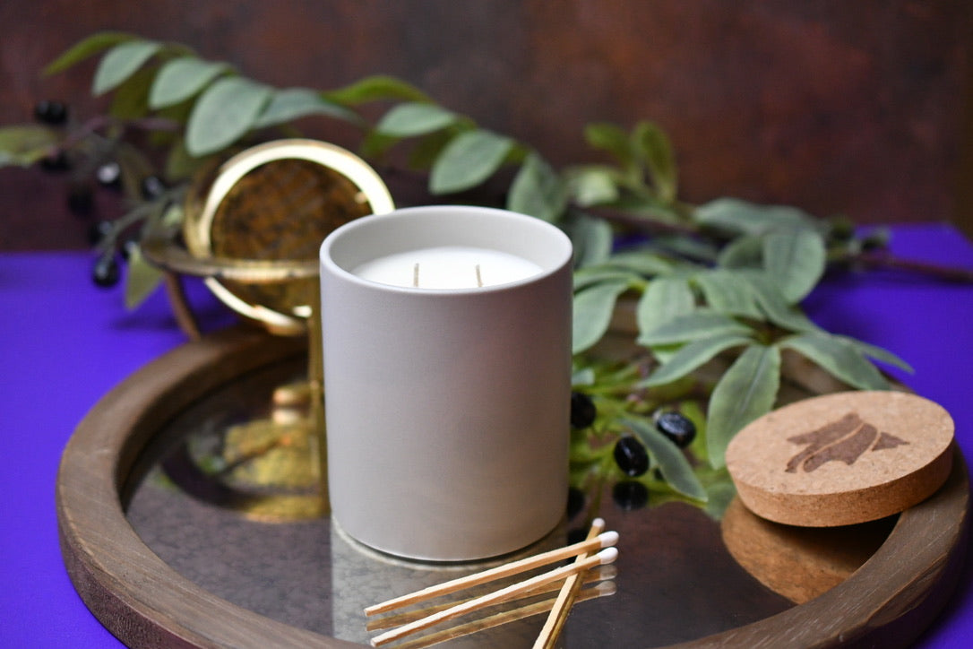 Stone dual wicked candle on reflective tray with white tipped matches and a hand-branded cork lid.