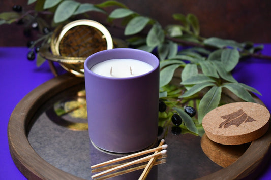 Purple dual wicked candle on reflective tray with white tipped matches and a hand-branded cork lid.