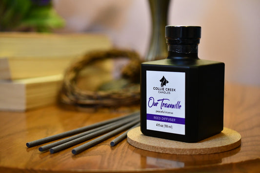 Collie Creek Candles diffuser bottle with gray reeds on a wooden surface