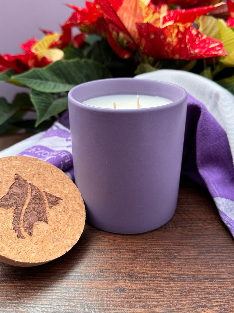 Double cotton wicked candle in purple vessel with branded cork lid in foreground.