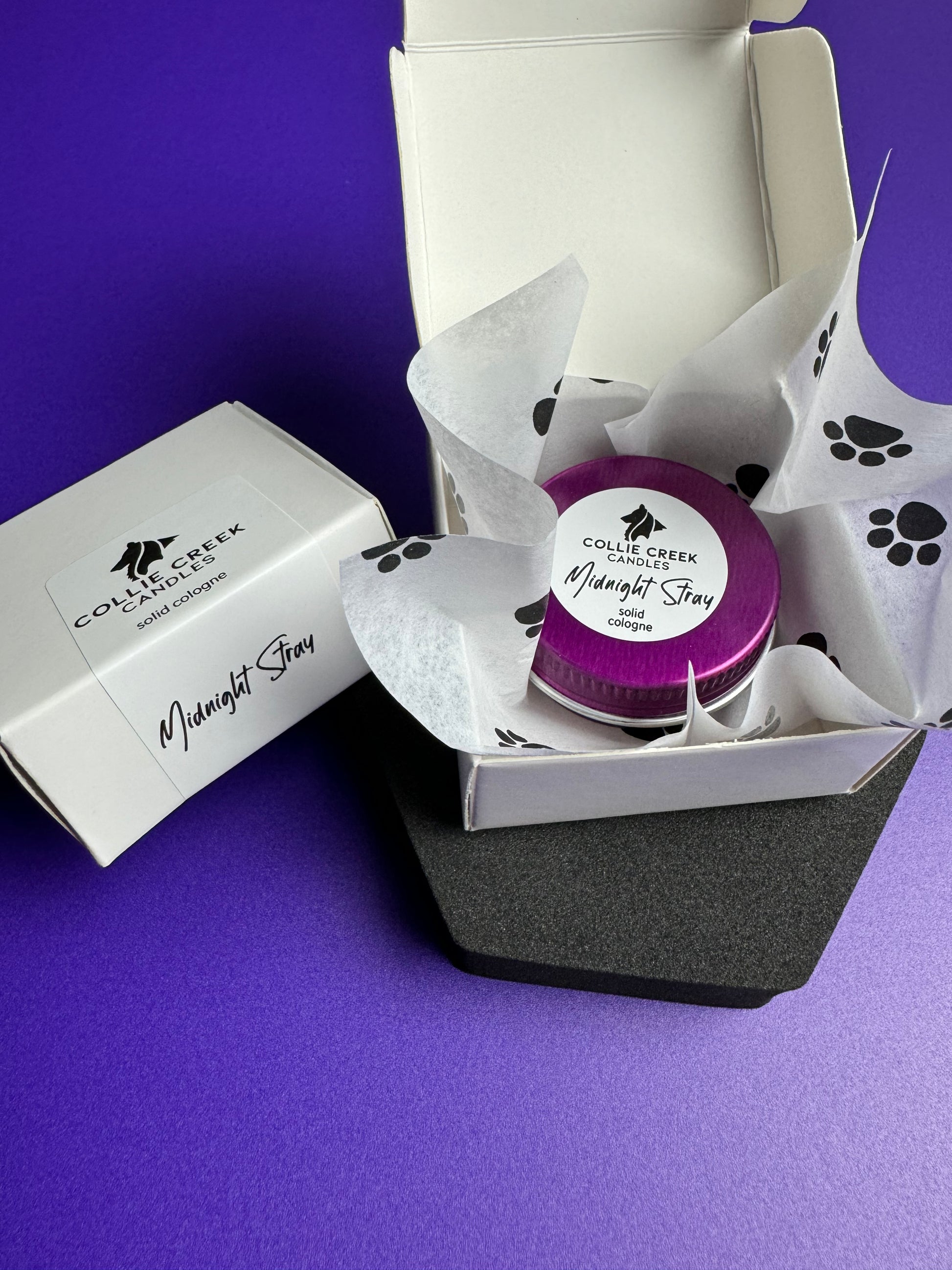 Solid colognes in lavender or patchouli scent in a purple tin paw print tissue paper white gift box.