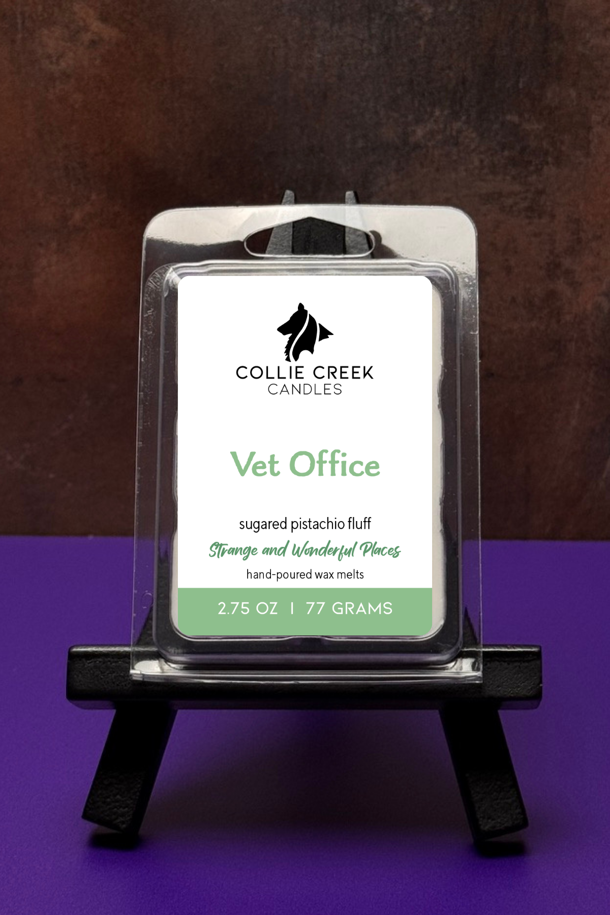Collie Creek Candles Vet Office wax melt packaging on a stand with a worn bronze and purple background