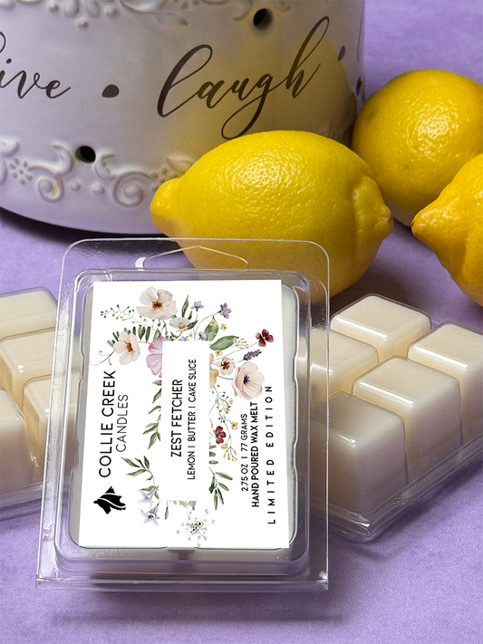 Natural colored wax melts in 6 cube clam shell. Floral designed label, 2.75 oz, 77 grams, limited edition. Set in display with bright yellow lemons on light purple background.