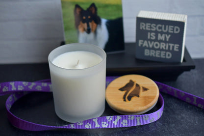 Single cotton wick 8oz candles in frosted white glass vessel. A purple and silver dog leash wraps around the products which feature a hand-branded wooden lid.