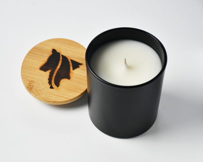Top view of a black matte candle product image featuring a single wick and hand branded Collie Creek Candles logo candle lid on white background.