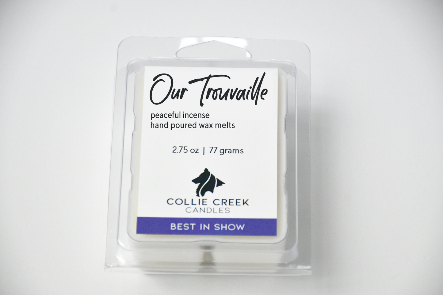 Our Trouvaille wax melt white label with black lettering and Collie Creek Candles logo. Bottom of label says "best in show" reversed type over purple box. Natural colored wax melts peek out behind the label.